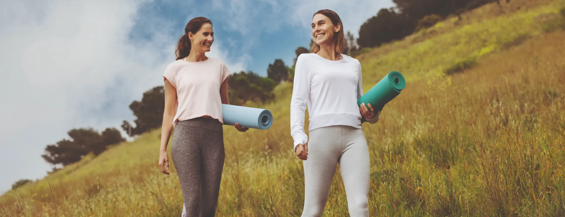 Two women walking through a lush field about to do a yoga class at Homefield Grange