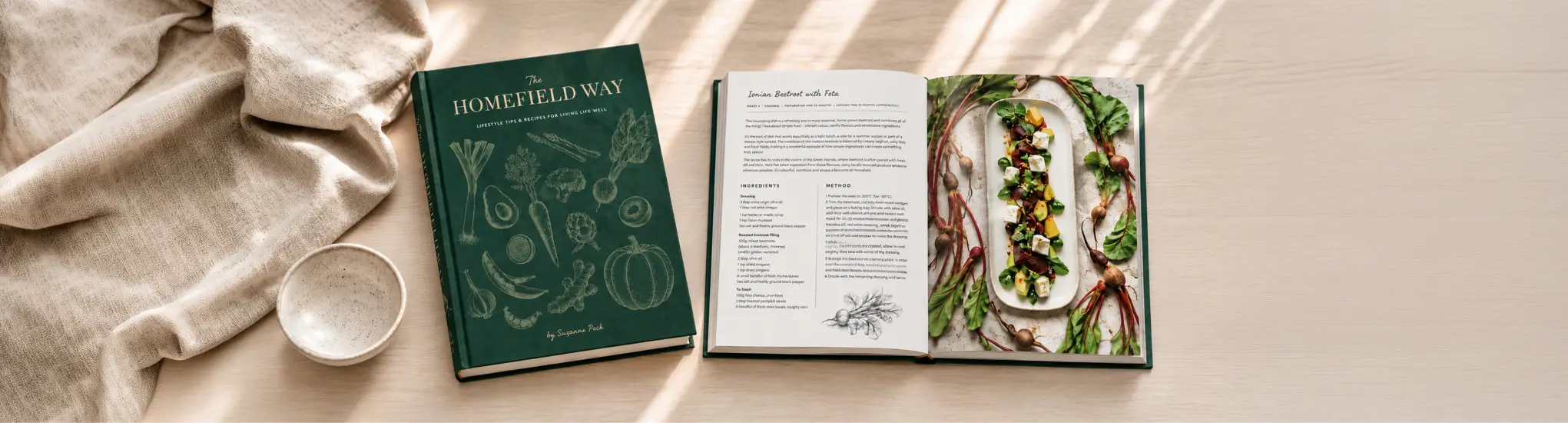 The Homefield Way cookbook by Suzanne Peck alongside an open recipe spread featuring a colourful plant-based dish.